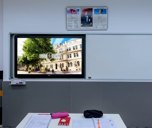 Teknolojinin eğitimdeki etkisi her geçen gün artıyor ve bu değişim özellikle öğretim yöntemlerinde köklü dönüşümlere yol açıyor. Akıllı tahta kullanımı, geleneksel sınıf yapılarının ötesine geçerek öğrencilerin öğrenme deneyimlerini ve öğretmenlerin öğretim biçimlerini yeniden şekillendiriyor. Bu yazıda, akıllı tahtaların sınıf dinamikleri üzerindeki etkilerini, eğitimde nasıl bir değişim sağladıklarını ve bu teknolojinin eğitim süreçlerinde ne gibi yenilikler getirdiğini inceleyeceğiz. Konulu bir haber görseli.