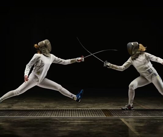 Eskrim, çok eski zamanlardan beri uygulanan bir dövüş sporudur. Klasik anlamda, rakiplerini bir kılıç veya kalkan ile alt etmeye çalışan dövüşçüler arasında geçen bir mücadele türüdür. Ancak günümüzde, eskrim, modern spor formatına dönüştürülmüş ve olimpiyat oyunlarına dahil edilmiştir. Eskrimde, sporcular hız, çeviklik, strateji ve teknik bilgilerini kullanarak rakiplerinin savunmalarını aşmaya çalışır. Eskrim, yalnızca fiziksel güç değil, aynı zamanda zekâ ve strateji gerektiren bir spordur. Hız, denge ve odaklanma gibi özelliklerin gelişmesine katkı sağlarken, rakibin hareketlerini tahmin etme ve doğru anı bekleyerek saldırma yeteneğini de geliştirir. Konulu bir haber görseli.